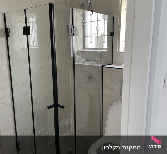 מקלחון פינתי מתקפל עם פרופיל שחור וזכוכית שקופה בחדר רחצה